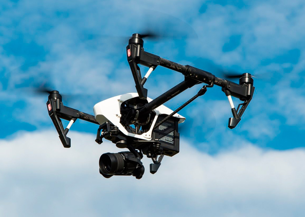 Dron volando en el aire bajo el cielo azul grabando
